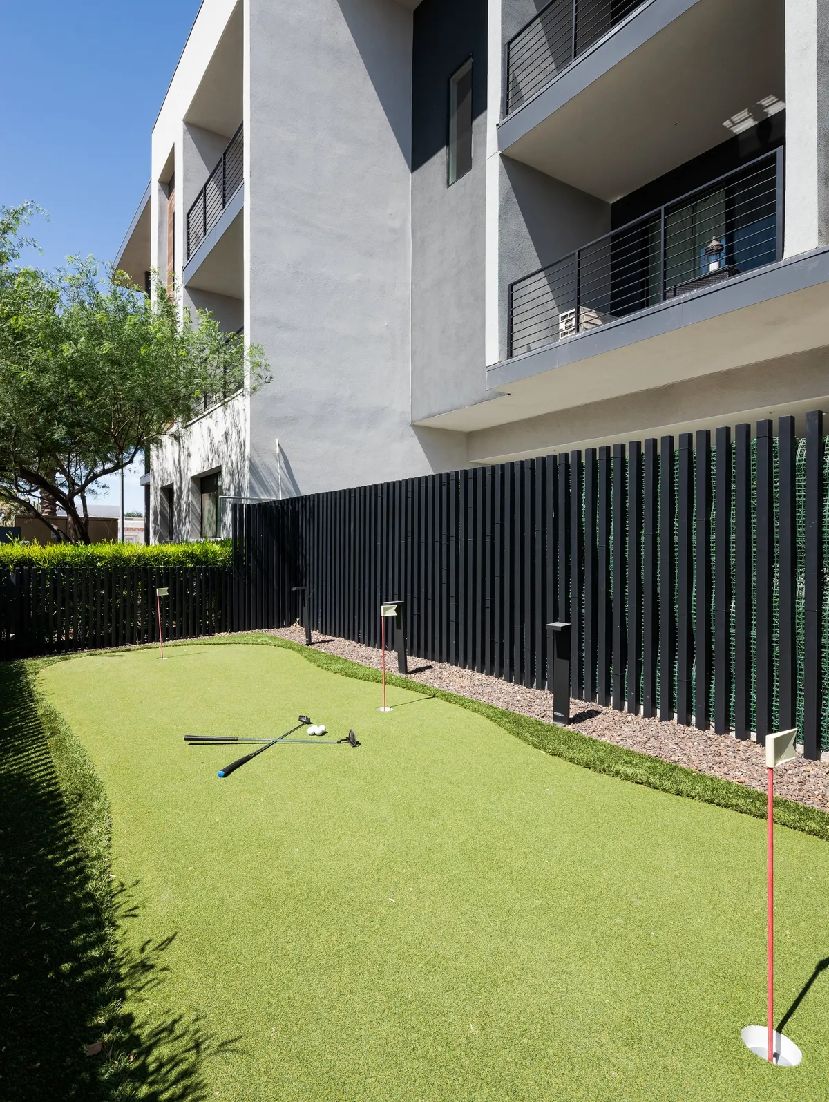 A landscaped exterior with a modern putting green set beside the building and surrounded by green spaces, offering a playful and relaxed environment for residents to socialize and practice golf.