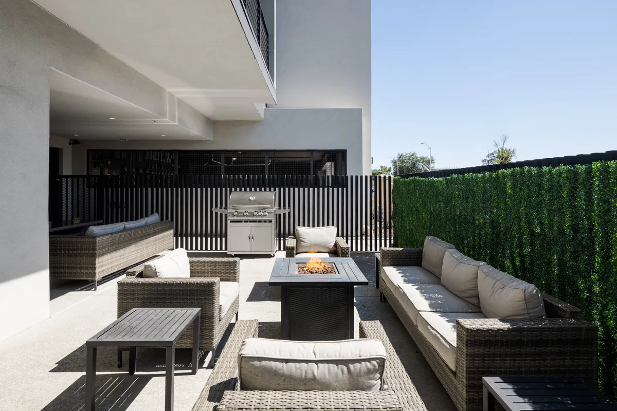An outdoor gathering space featuring a cozy fire pit, comfortable seating, and a BBQ grill. The area feels casual and inviting, ideal for sunset gatherings, barbecues with friends, and cozy evenings by the fire.